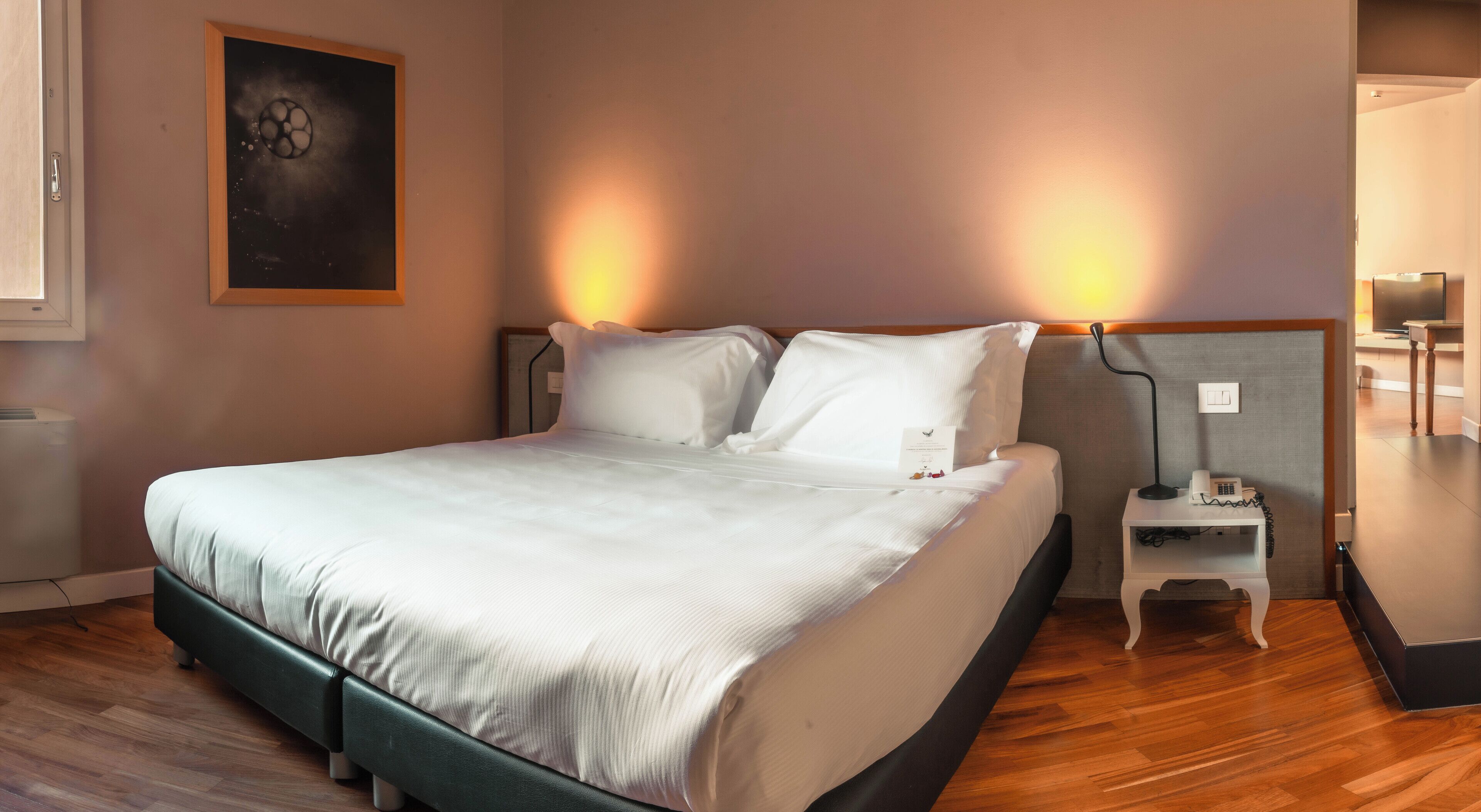 A neatly made bed with white linens in a hotel room.