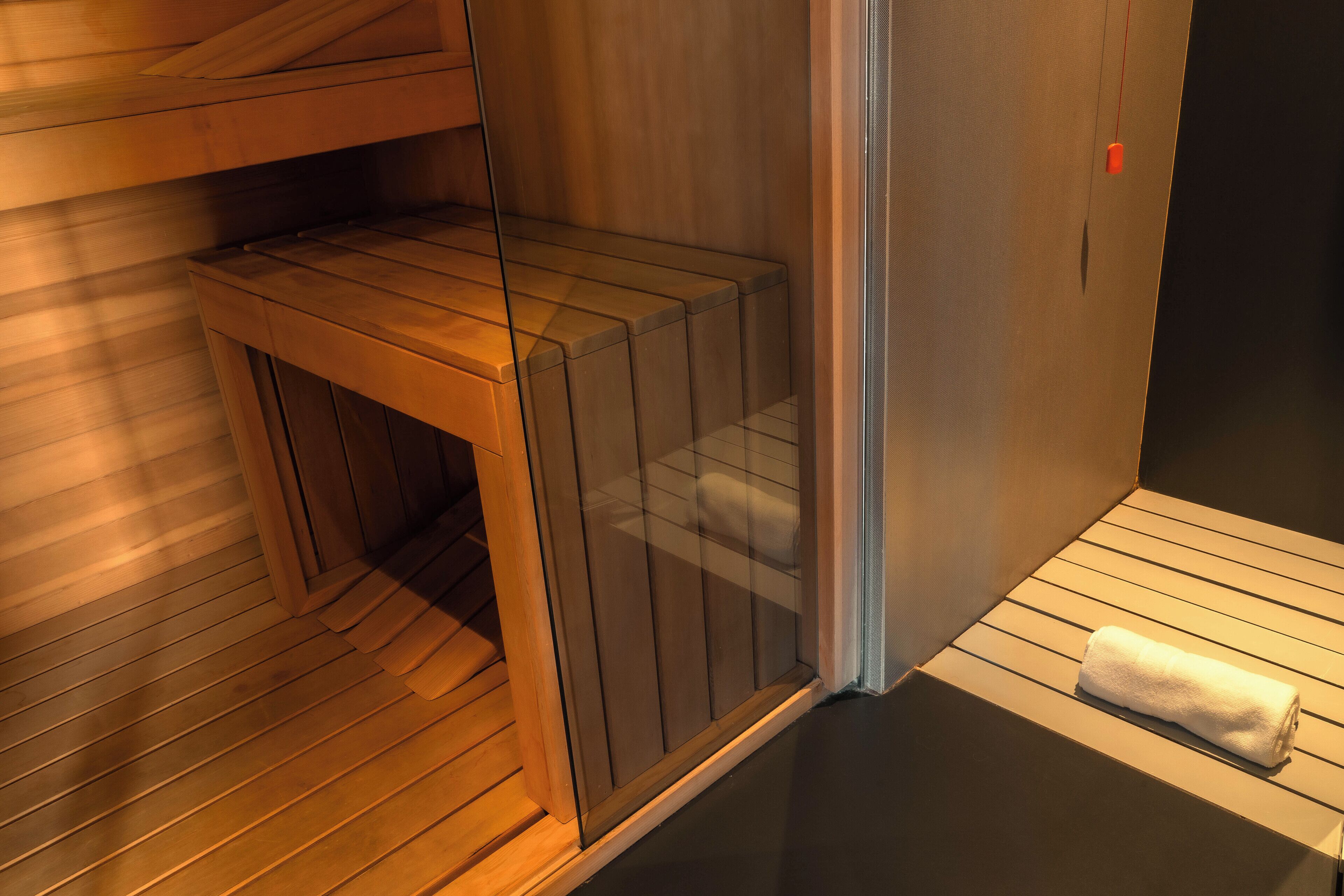 Un sauna avec des bancs en bois et une porte en verre.