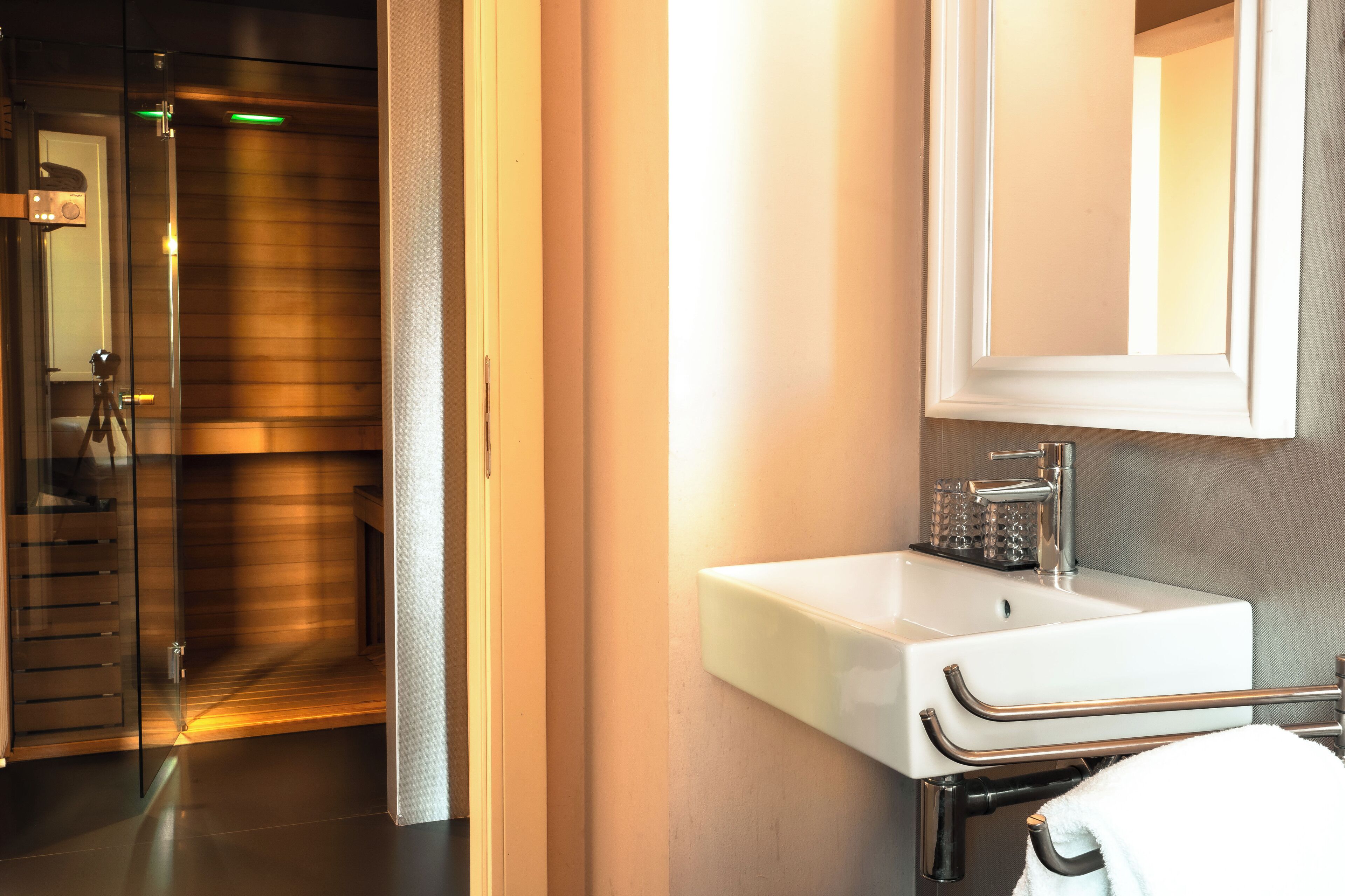 Un baño moderno con cabina de ducha de vidrio, un lavamanos blanco con toallero y un espejo sobre el lavamanos.