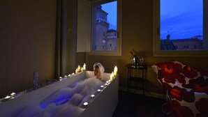 A bathtub with candles and a view of a building through a window. - Casa d'Este - Hotel Ferrara (Ferrara)