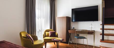 A modern living room with a sofa, two armchairs, a coffee table, a TV, and a staircase.