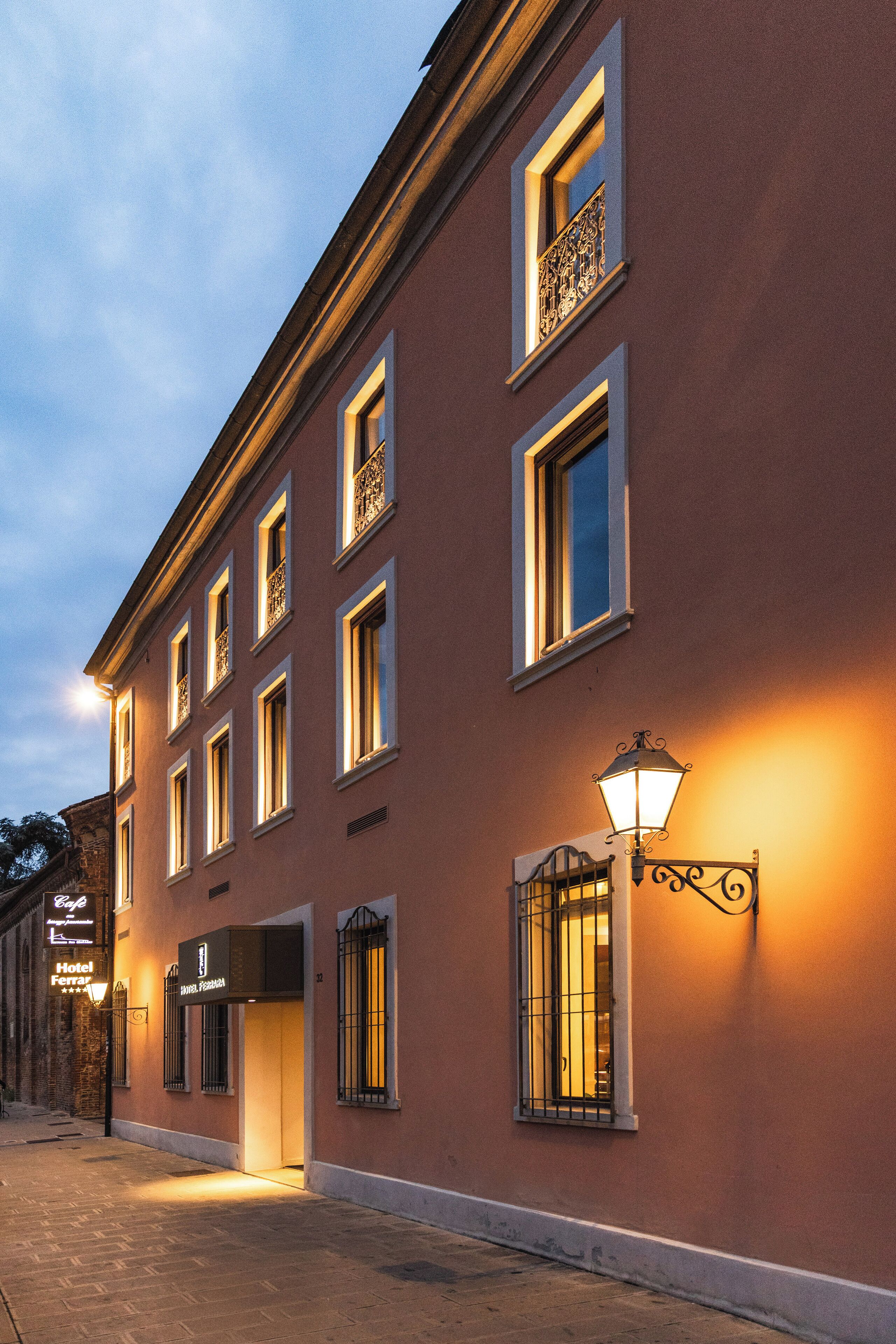 A historic building with multiple windows, a ground-floor entrance, and a street lamp.