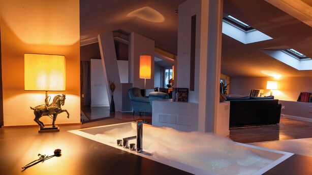 A modern living room with a central white bathtub, a statue, and two lamps. - Casa d'Este - Hotel Ferrara (Ferrara)