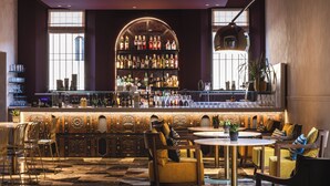 A bar area with a high bar counter, shelves of bottles, and seating with chairs and tables. - Casa d'Este - Hotel Ferrara (Ferrara)