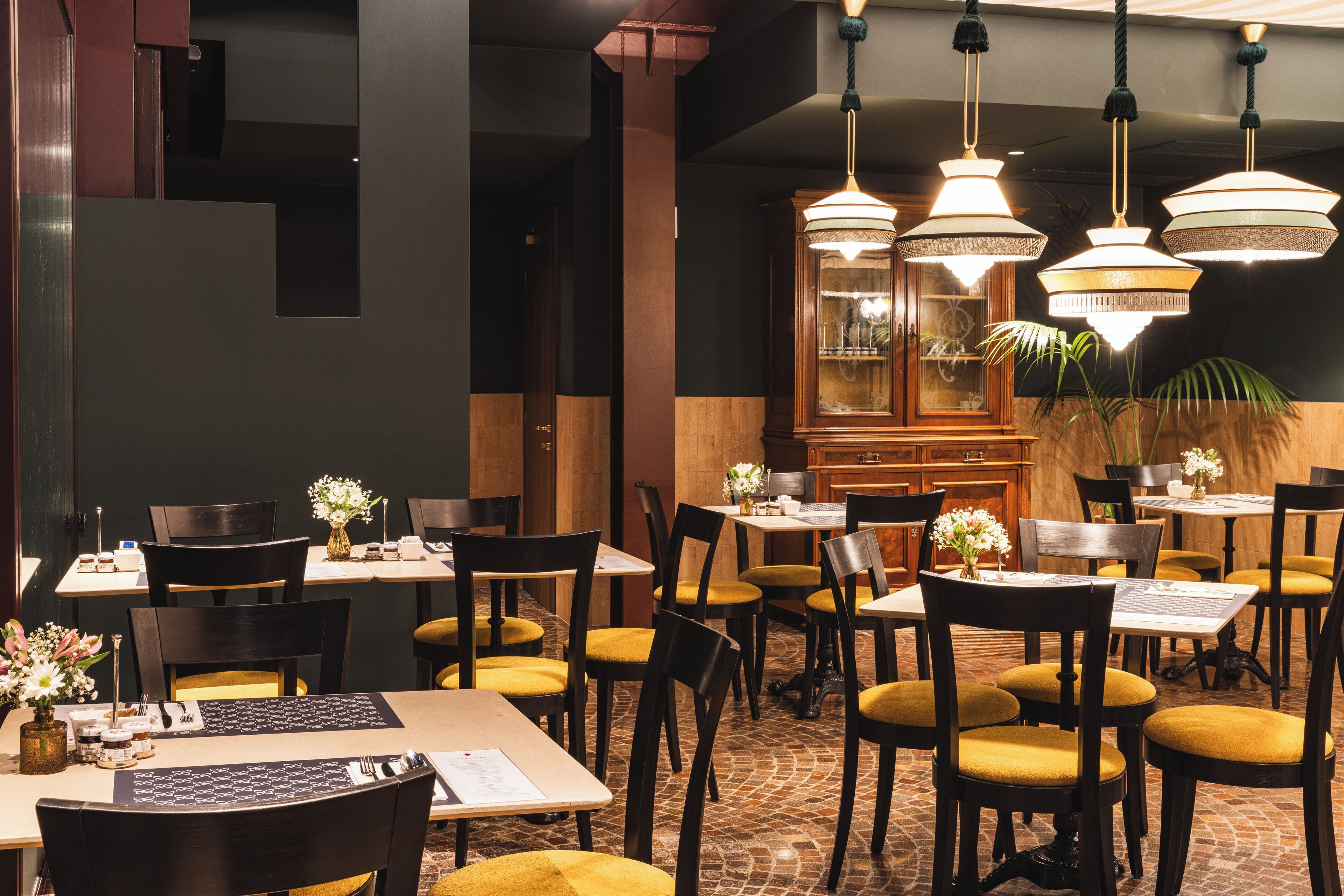 Ein Restaurantinneres mit Tischen, Stühlen und hängenden Kronleuchtern.