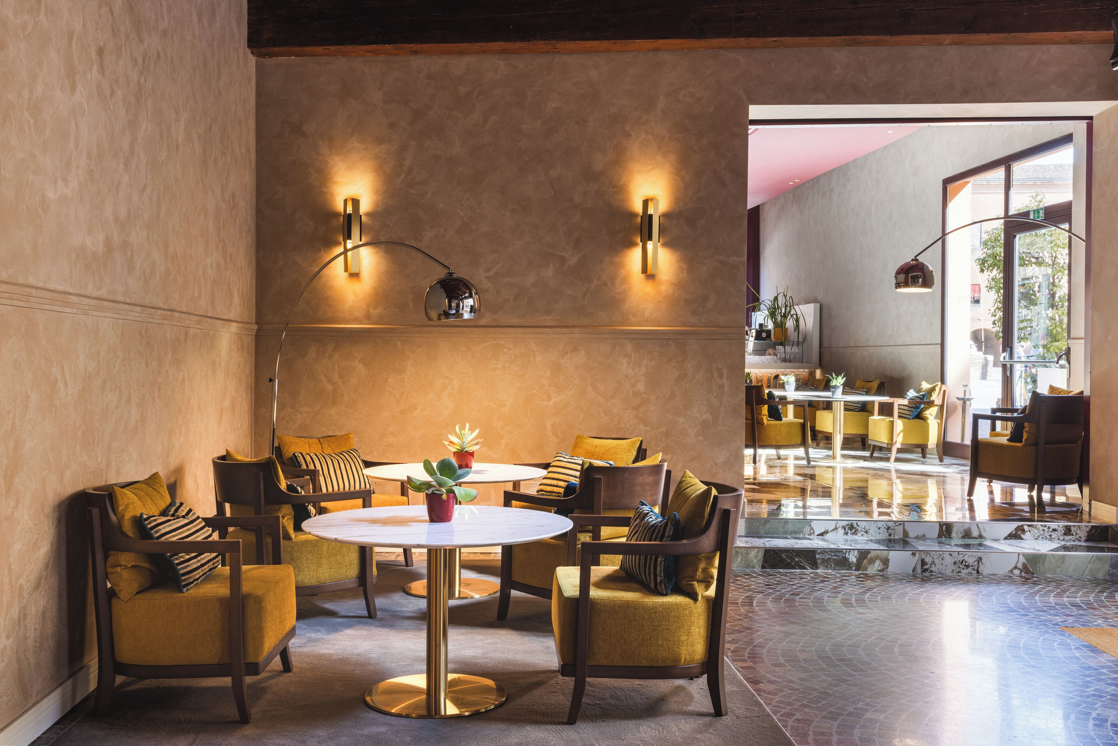 Um interior moderno com uma mesa redonda cercada por cadeiras amarelas, um sofá e uma mesa de centro com plantas.