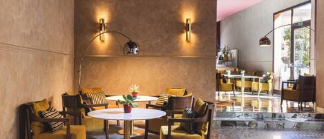Um interior moderno com uma mesa redonda cercada por cadeiras amarelas, um sofá e uma mesa de centro com plantas.