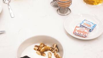 A breakfast table with various food items, including eggs, a bowl of yogurt with fruits, and a plate of pastries.