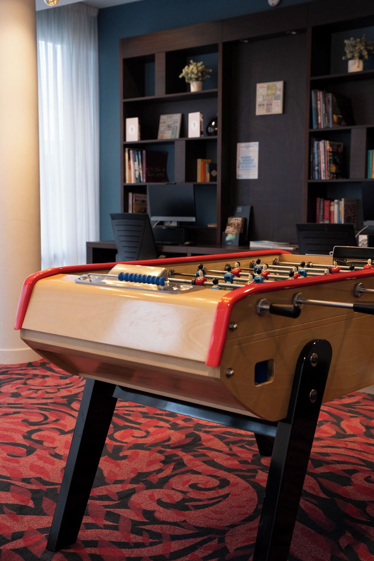 Una mesa de fútbol de mesa en una habitación con una estantería y un escritorio.