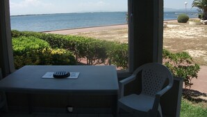 Une terrasse avec une table et une chaise, donnant sur une plage et la mer.