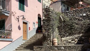 Una escalera de piedra que lleva a un edificio con puerta de madera y un pequeño jardín.