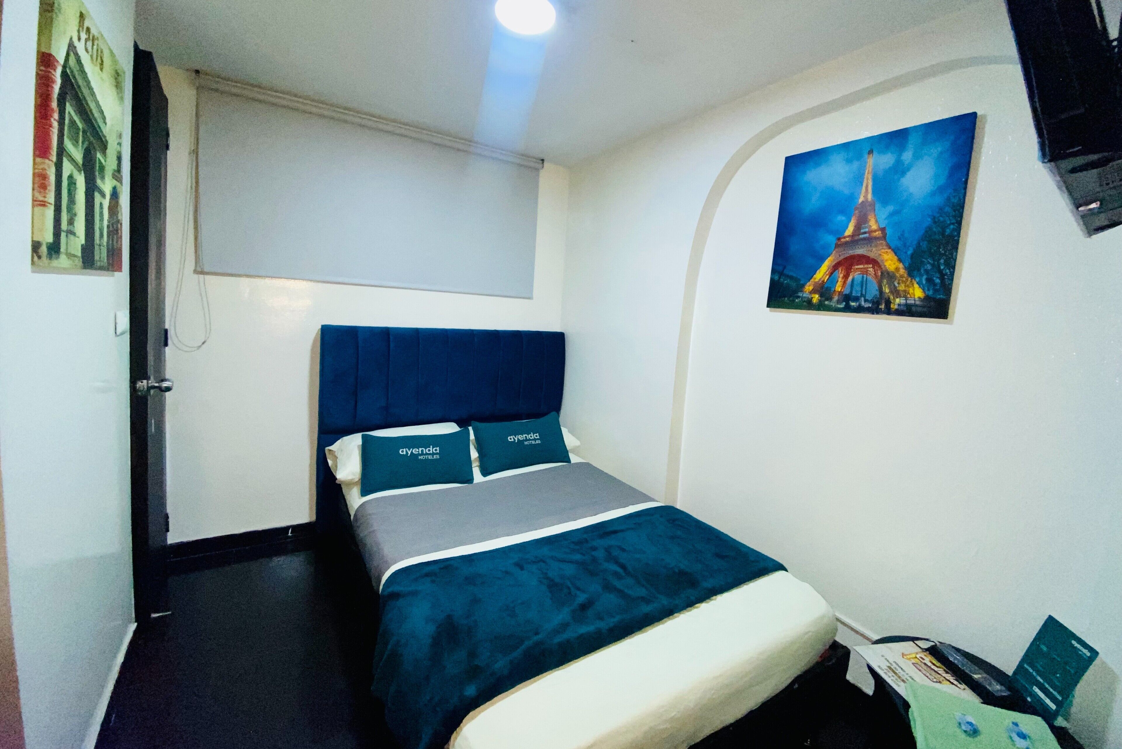 Ein Hotelzimmer mit einem Bett, einem Fenster, einer Tür und einem Bild vom Eiffelturm.