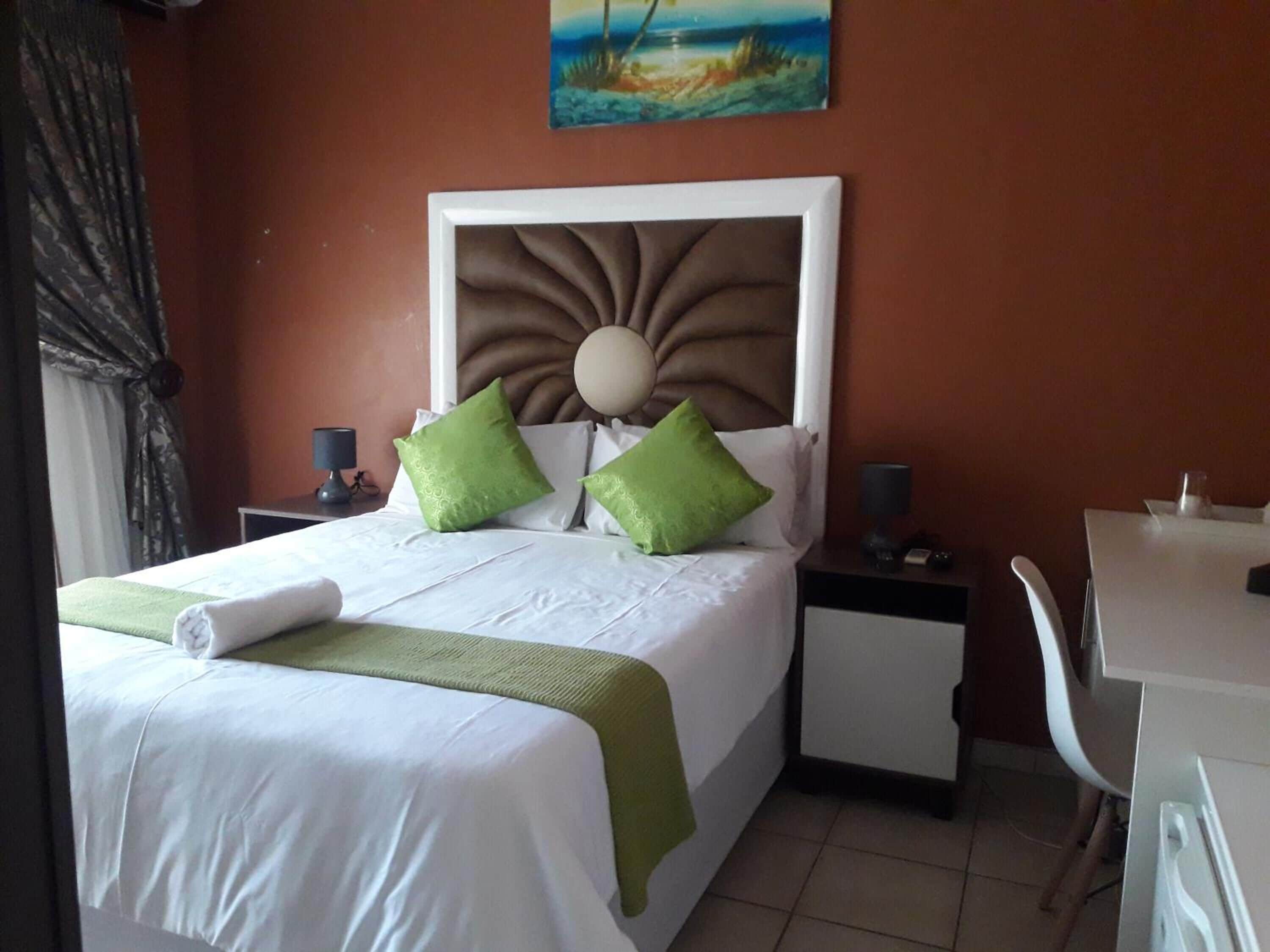 Ein Hotelzimmer mit Bett, Schreibtisch, Stuhl und einem Bild an der Wand.