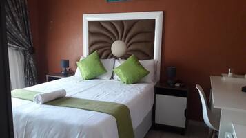 Ein Hotelzimmer mit Bett, Schreibtisch, Stuhl und einem Bild an der Wand.