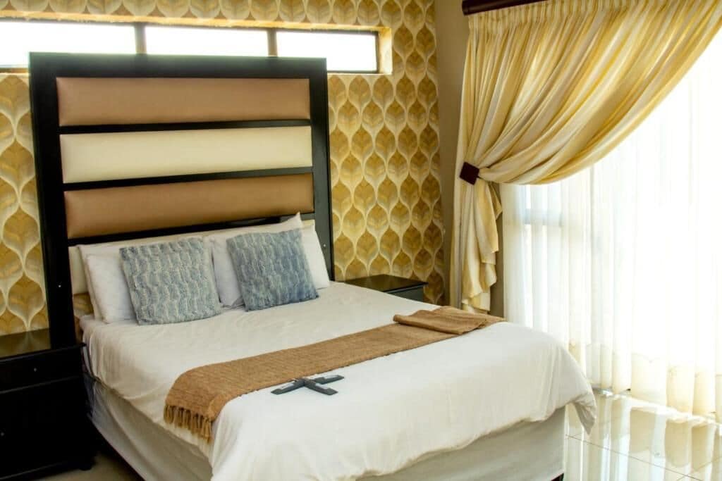 A neatly made bed with a headboard, two pillows, and a blanket.