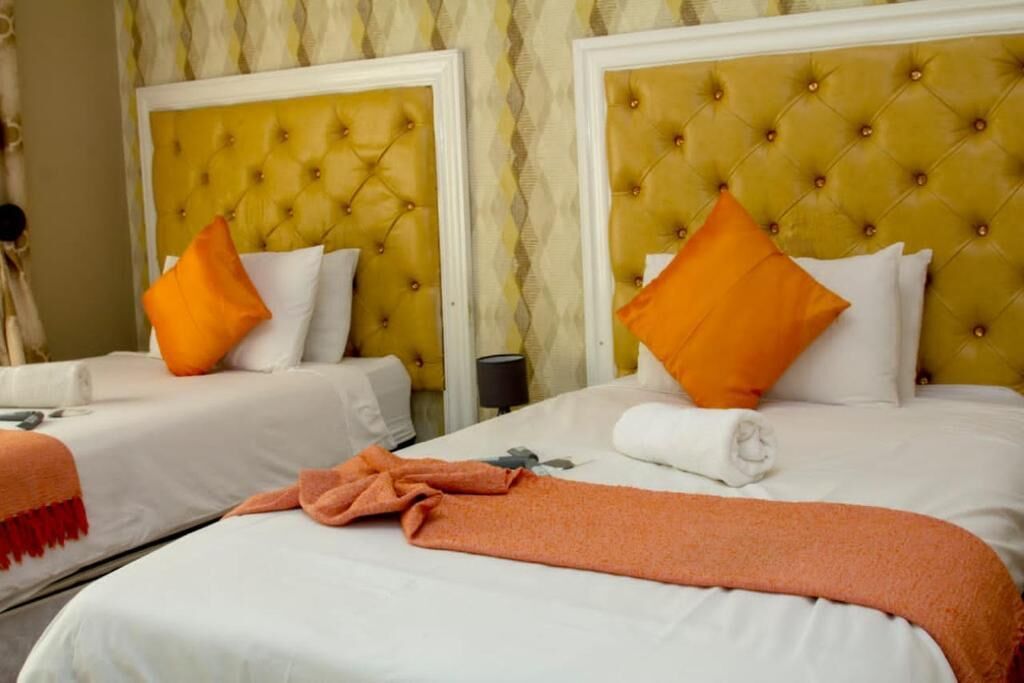 Habitación de hotel con dos camas, cada una con cabecera capitonada y ropa blanca.