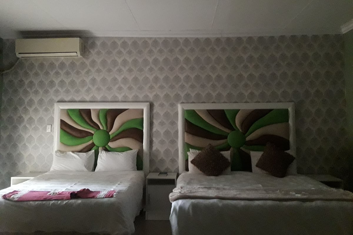 Een hotelkamer met twee bedden, elk met een ander hoofdeinde.
