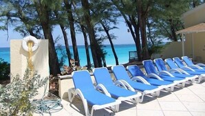 Zona junto a la piscina con sillas reclinables azules, una piscina y vista al océano.
