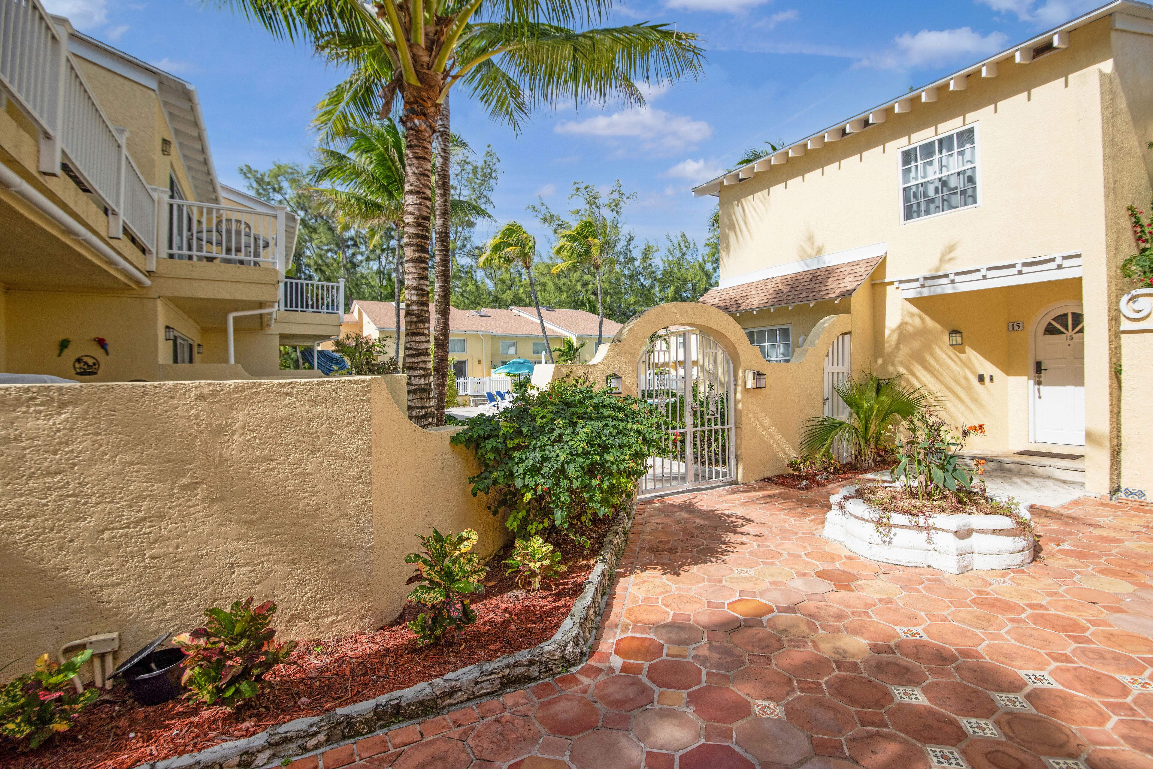 A courtyard with a tiled floor, a palm tree, and a small garden area.