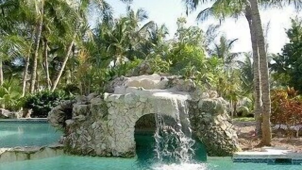 Una piscina con una formación rocosa natural y una cascada.