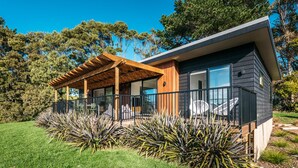 Une maison moderne dotée d’une pergola en bois, de grandes fenêtres et d’un jardin bien entretenu.