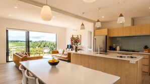 Une cuisine moderne dotée d’un grand îlot central, de meubles en bois et offrant une vue sur la campagne.