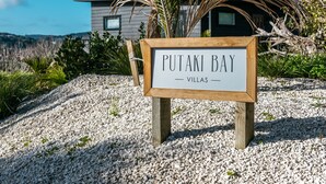 Une enseigne indiquant l’emplacement des villas de Putaki Bay, avec un bâtiment moderne en arrière-plan.