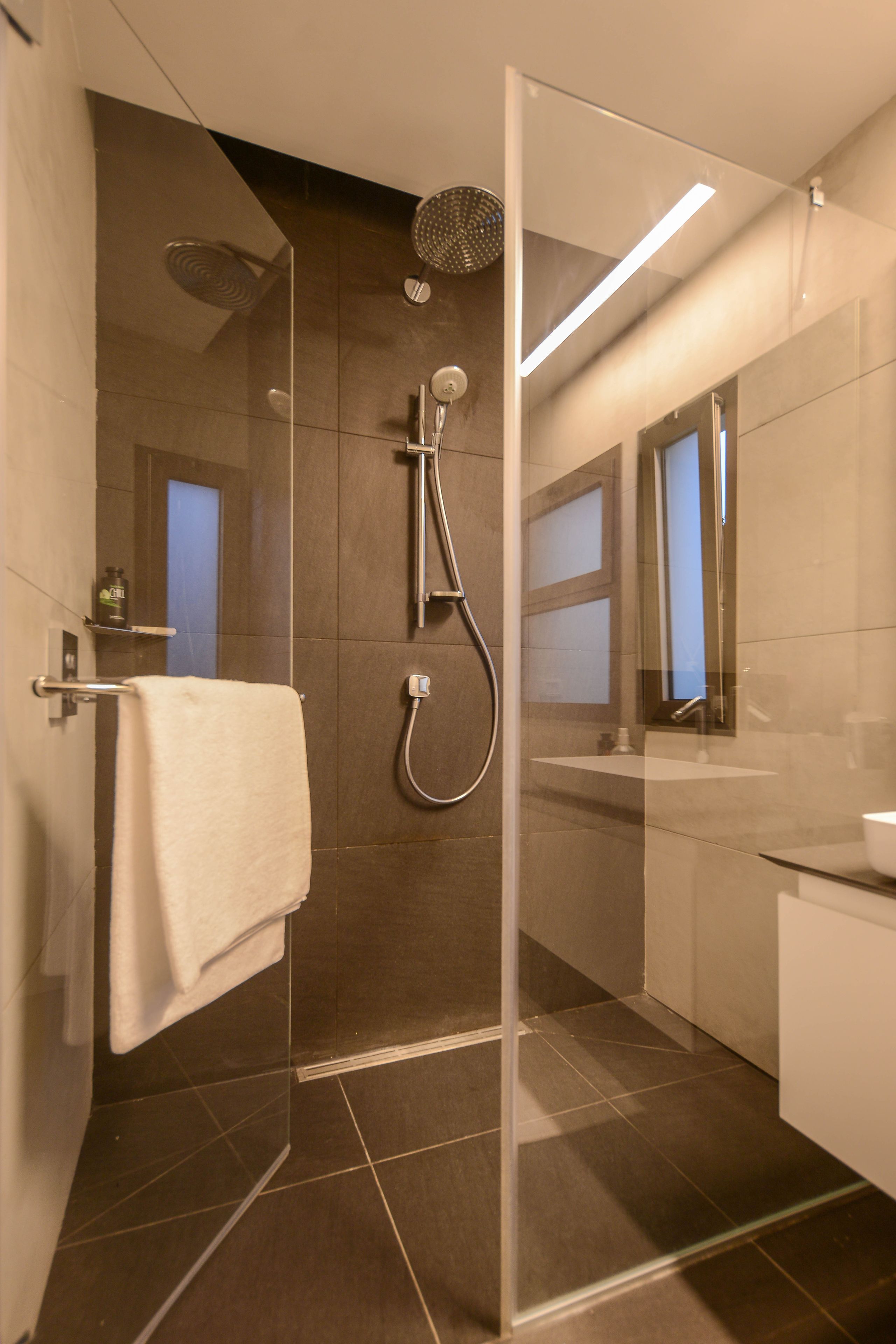 A modern bathroom with a glass-enclosed shower, a white sink, and a mirror.