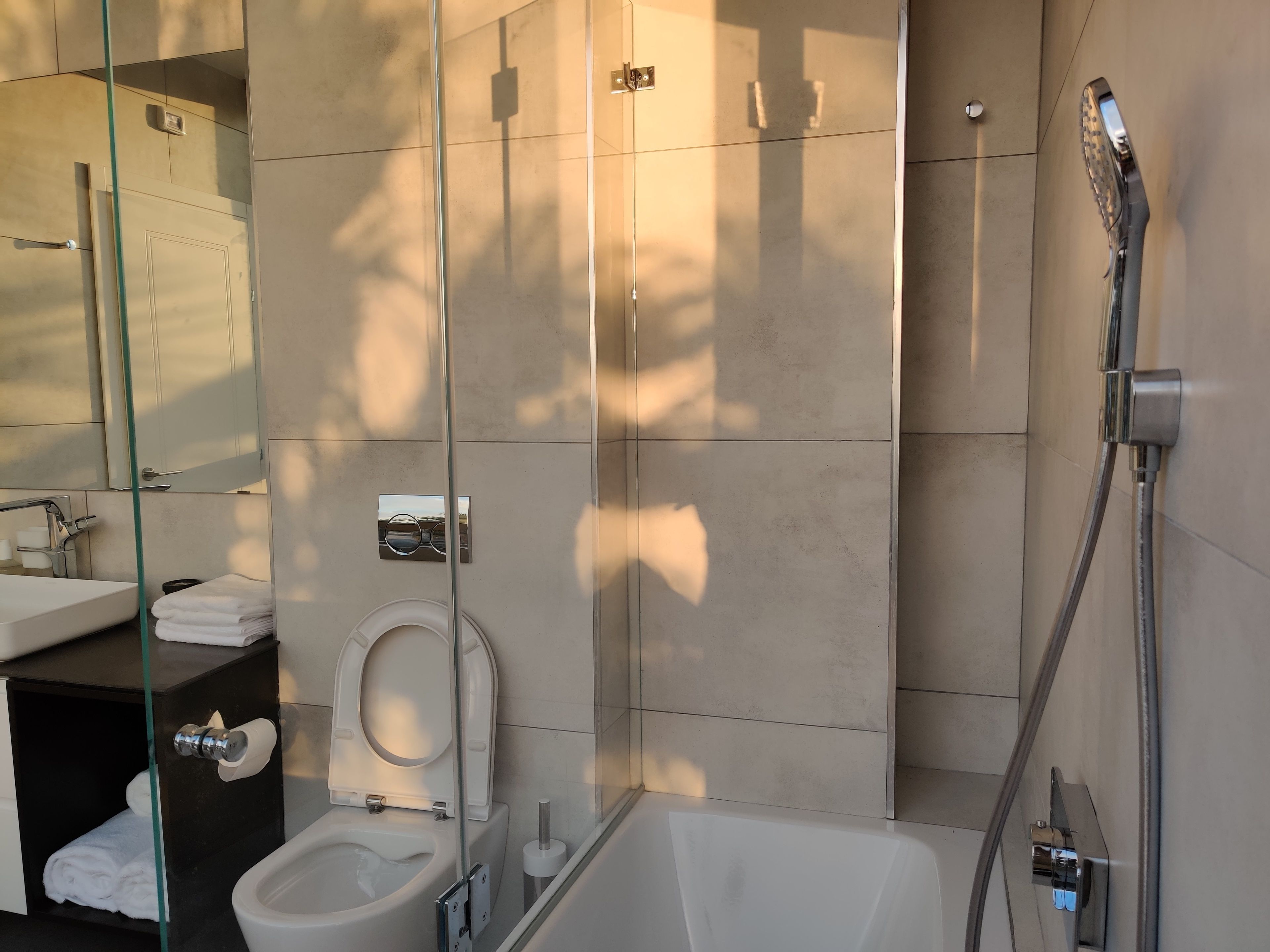 Uma casa de banho moderna com sanita, lavatório e chuveiro.