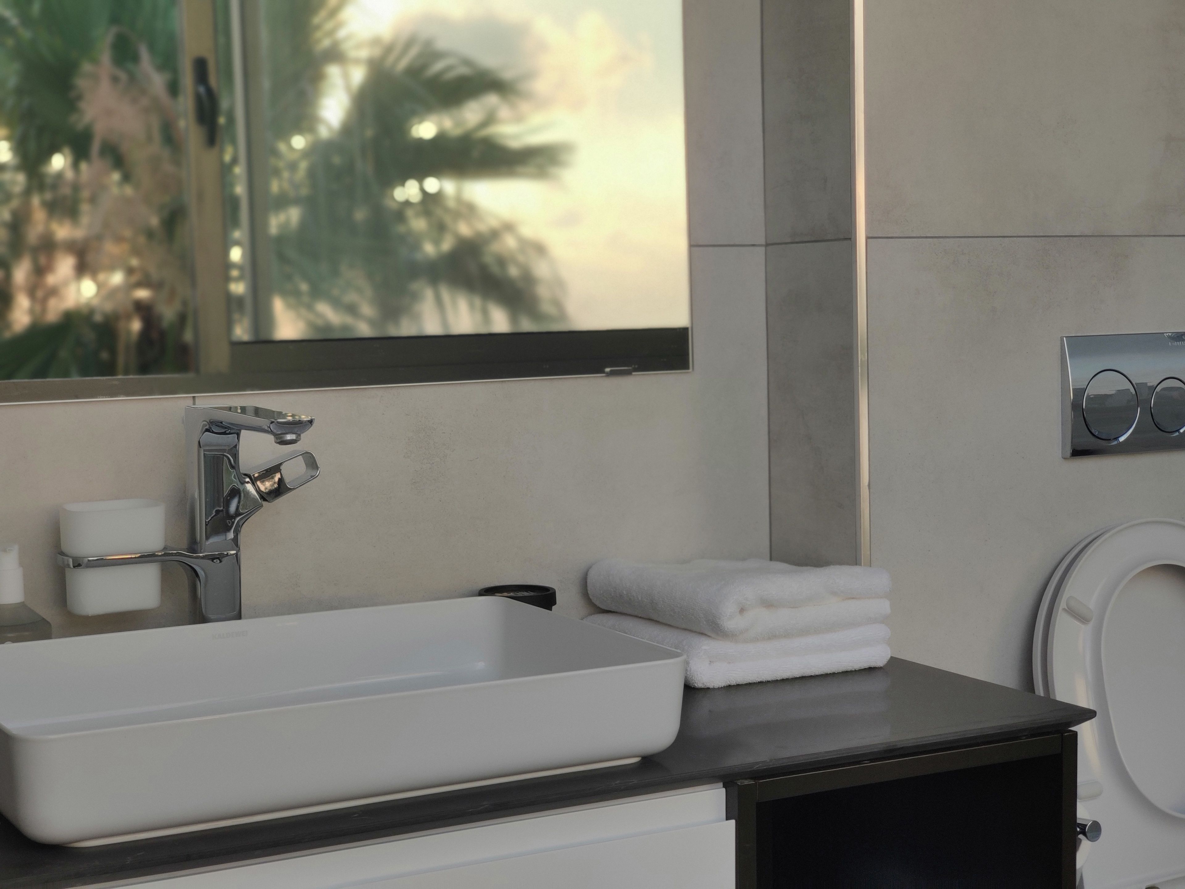 Un baño moderno con un lavamanos grande y rectangular, un espejo y un inodoro.
