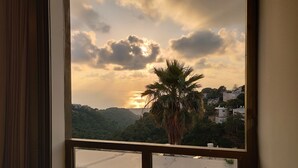 Vista dalla finestra su una zona residenziale, con una palma e case sullo sfondo.