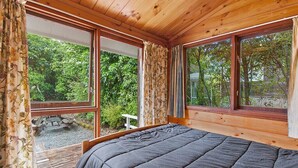 A bedroom with a large bed, wooden ceiling, and large windows offering a view of the outdoors. - Little Lockwood - Kuratau Bach (Kuratau)