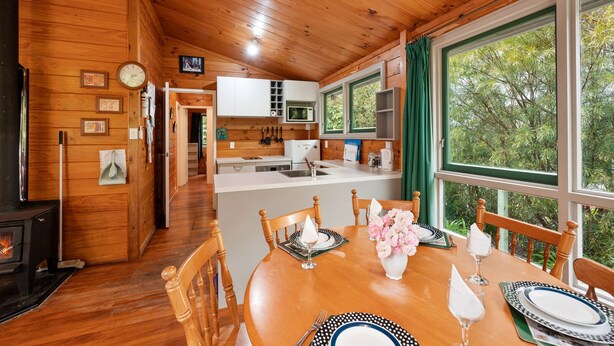 A wooden cabin with a dining area, kitchen, and a fireplace. - Little Lockwood - Kuratau Bach (Kuratau)