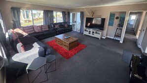 Een moderne woonkamer met een hoekbank, een salontafel en een flatscreen televisie.
