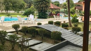 Un área de piscina con sillones de descanso y un pabellón.