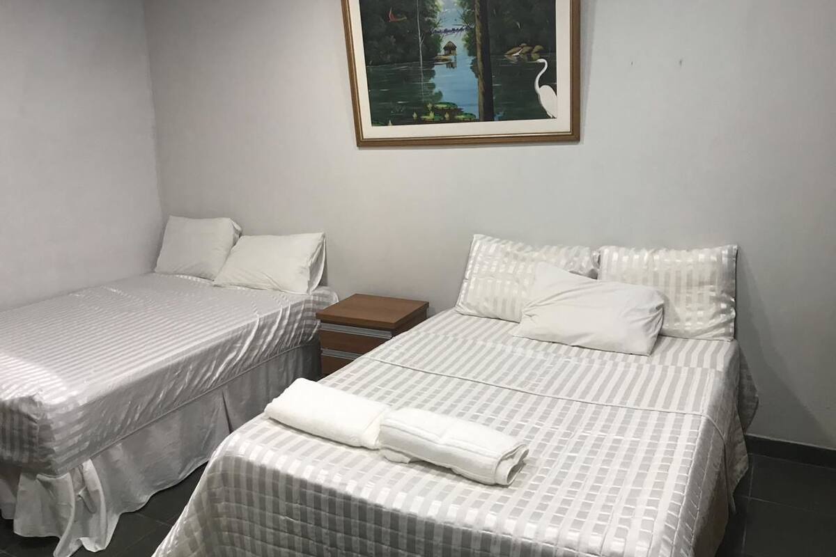 Una habitación de hotel con dos camas, una mesita de noche de madera y un cuadro enmarcado en la pared.