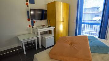 Una habitación de hotel con cama, escritorio, televisor y armario.