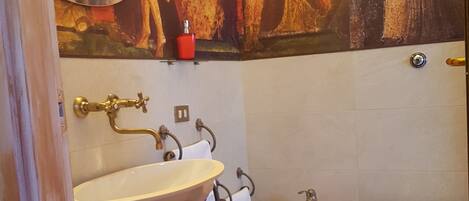 A bathroom with a sink, bidet, toilet, and a decorative wall painting.
