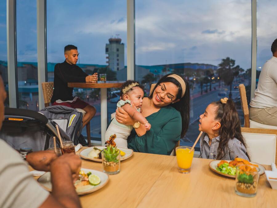 A family dining at a restaurant with large windows offering a view of the cityscape.