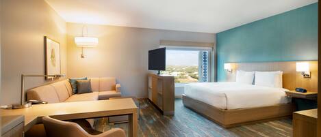 A hotel room with a bed, a desk, a chair, a TV, and a window with a view.