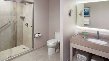 A modern bathroom with a glass-enclosed shower, a toilet, and a vanity with a sink and mirror.
