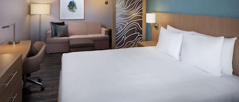 Una habitación de hotel con una cama grande, un sofá, un escritorio y una silla.