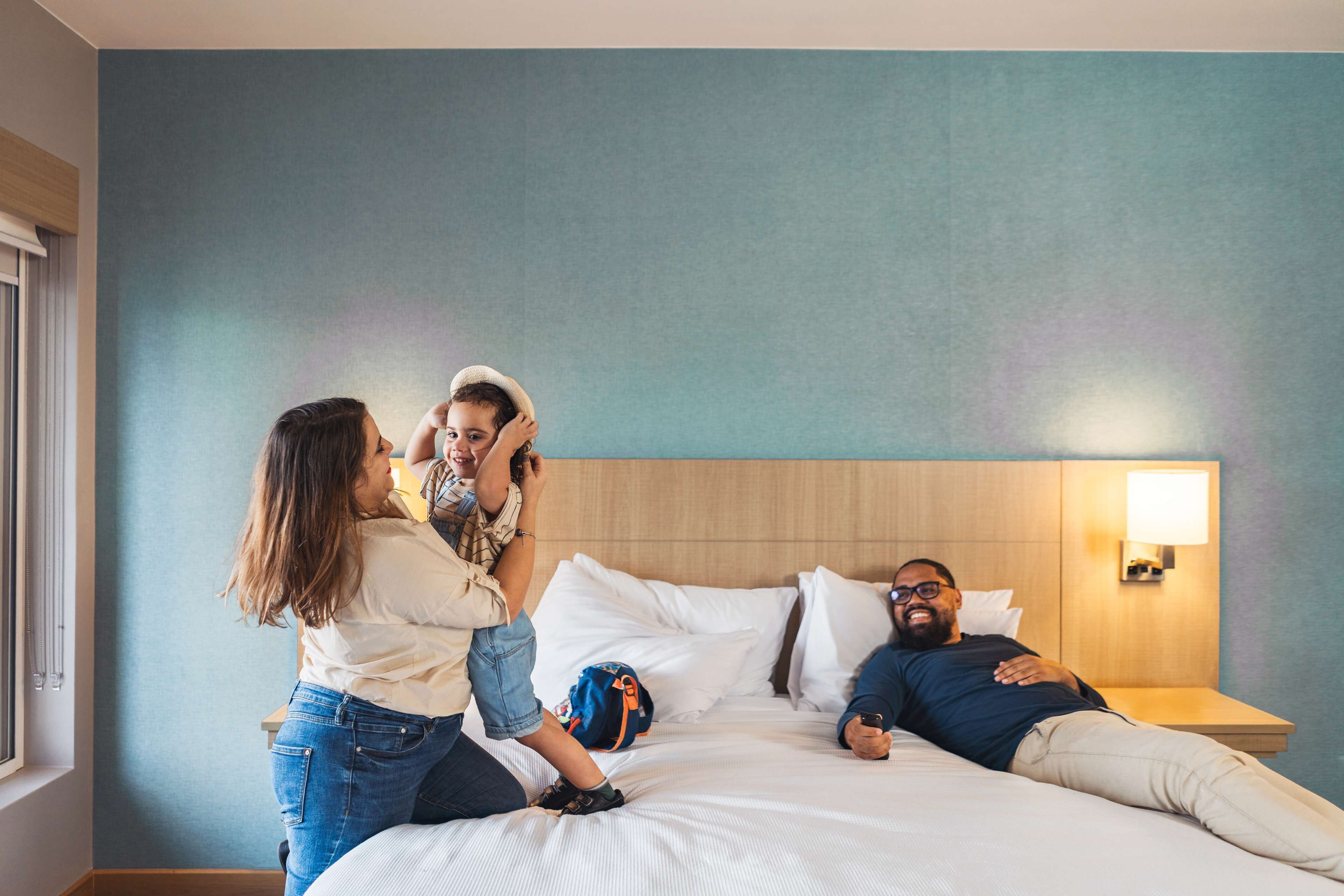 A hotel room with a bed, a nightstand, and a window.