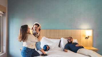 A hotel room with a bed, a nightstand, and a window.