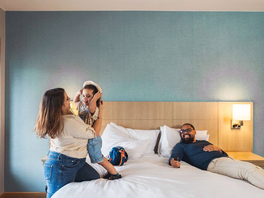 A hotel room with a bed, a nightstand, and a window.