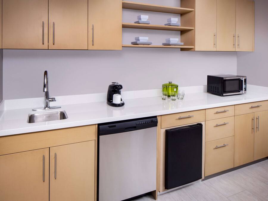 Una cocina moderna equipada con lavavajillas, cafetera, microondas y un lavabo.