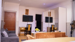 Habitación de hotel con cama, escritorio, silla, televisor y espejo.