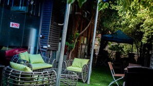 Sillas de mimbre con cojines verdes, un paraguas azul y un letrero que dice 'NO SHOW' en un edificio.