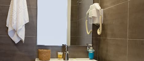 A bathroom with a white vanity, a mirror, a towel rack, a hairdryer, and a soap dispenser.
