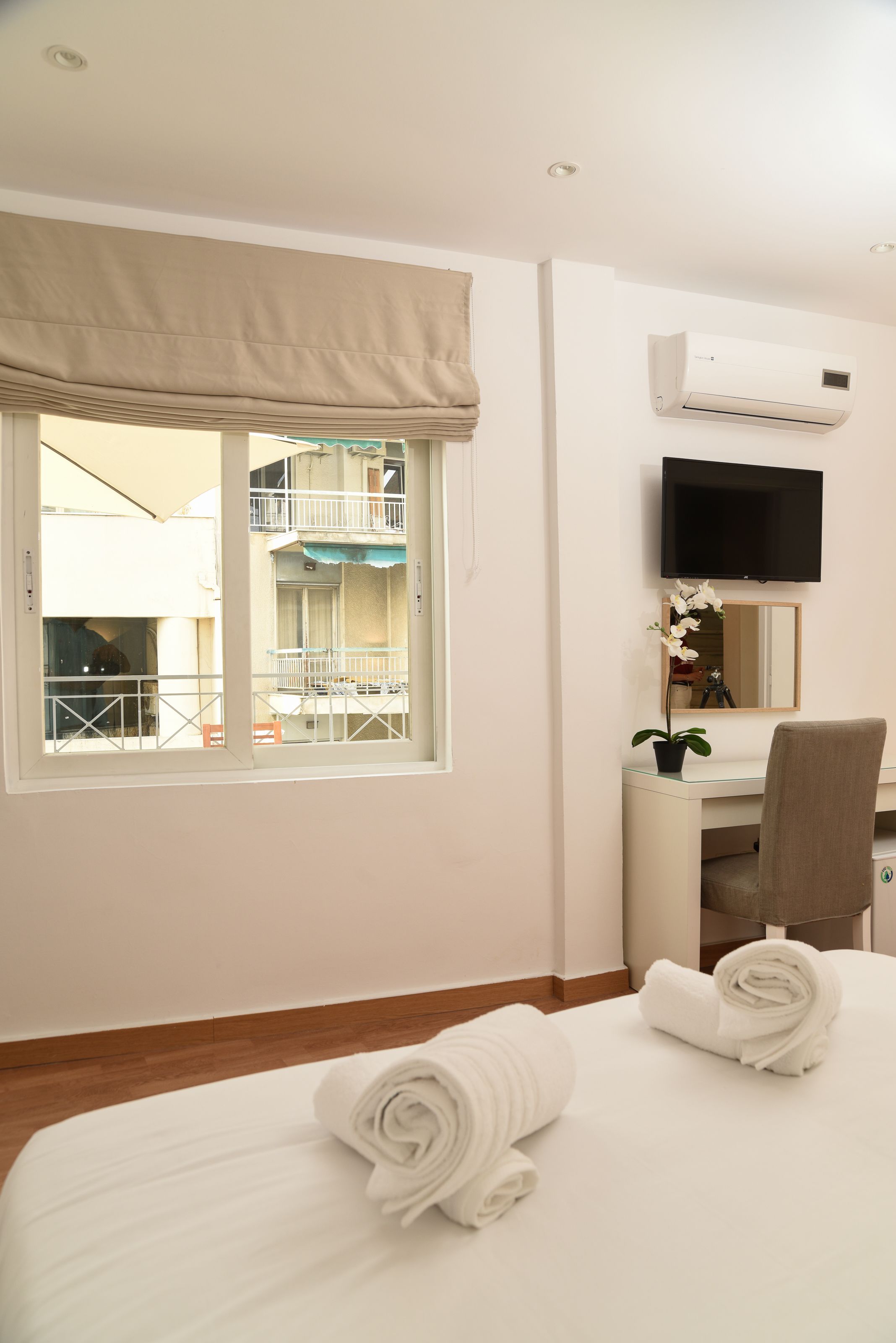 Une chambre d’hôtel comprenant un lit, un bureau, une chaise, une télévision et une fenêtre donnant sur un balcon.
